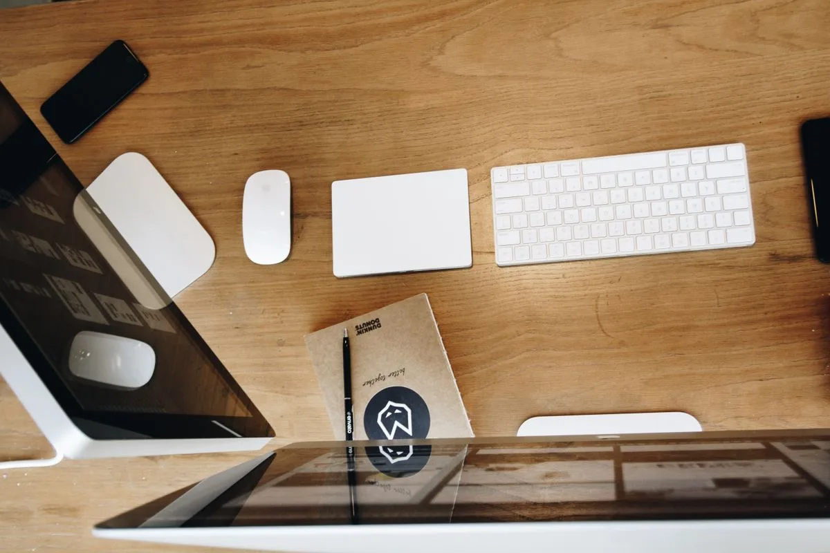 Aufgeräumter Schreibtisch mit Apple-Tastatur, Maus und Laptop