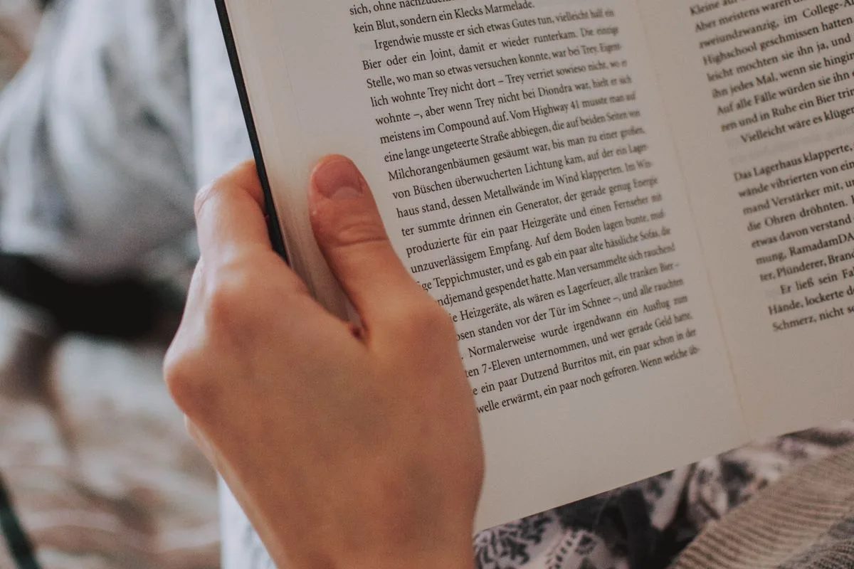 Hand hält ein aufgeschlagenes Buch, Nahaufnahme der Seiten