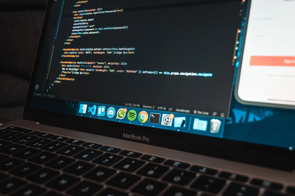 MacBook mit Programmcode auf dem Bildschirm in dunkler Umgebung
