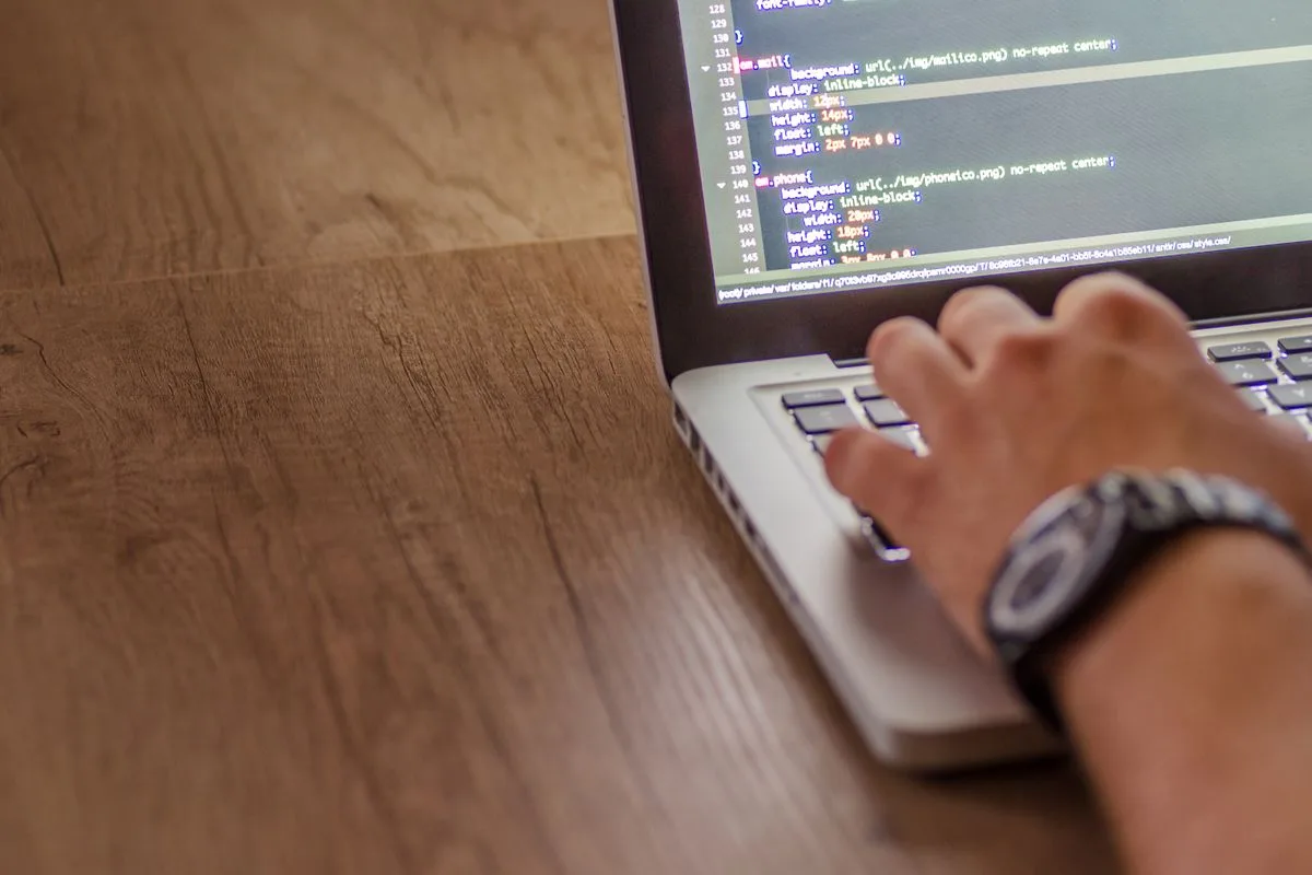 Hände tippen auf einem Laptop mit Code auf dem Bildschirm