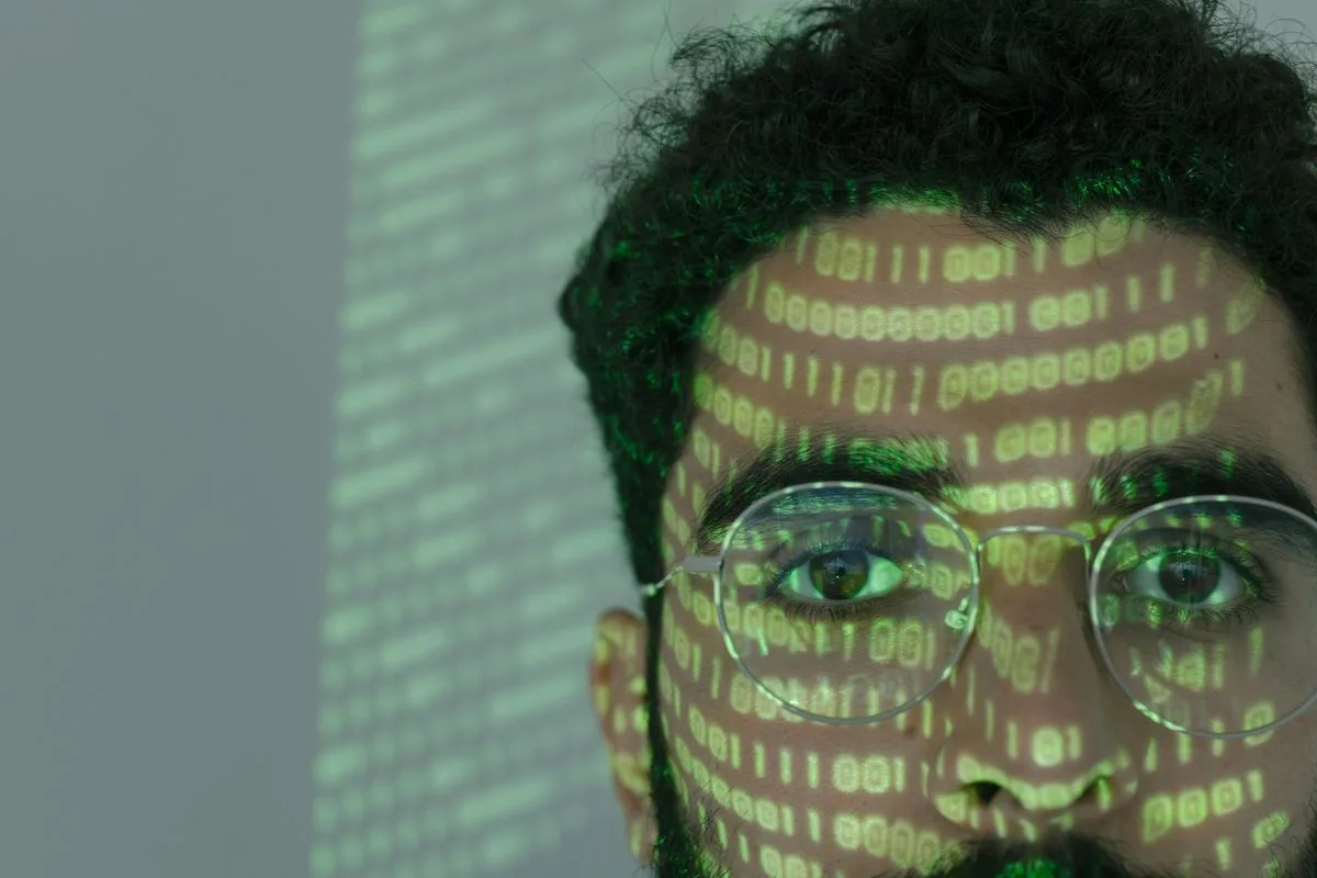 Gesicht einer Person, beleuchtet von grünem projiziertem Code