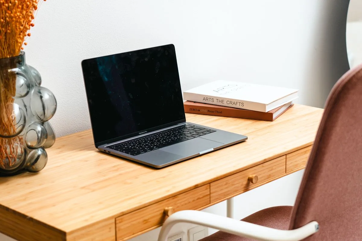 Holzschreibtisch mit Laptop, Zimmerpflanze und Büchern