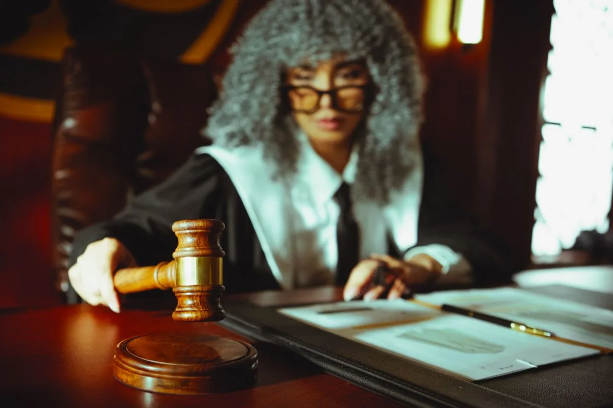 Person mit Richterhammer an einem Tisch im Halbdunkel