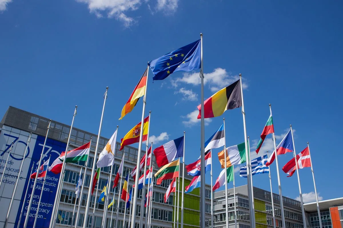 Wehende EU- und Länderflaggen vor blauem Himmel