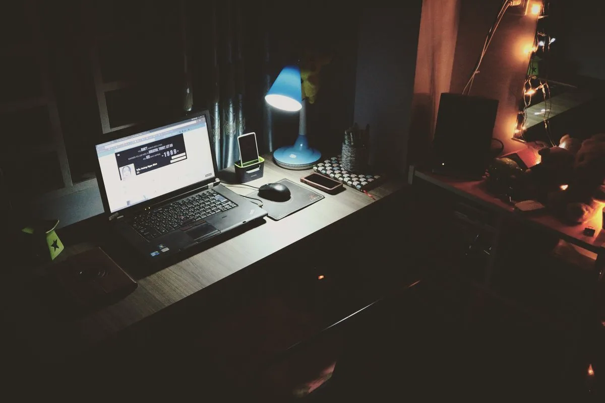 Laptop auf einem Schreibtisch in einem abgedunkelten Raum
